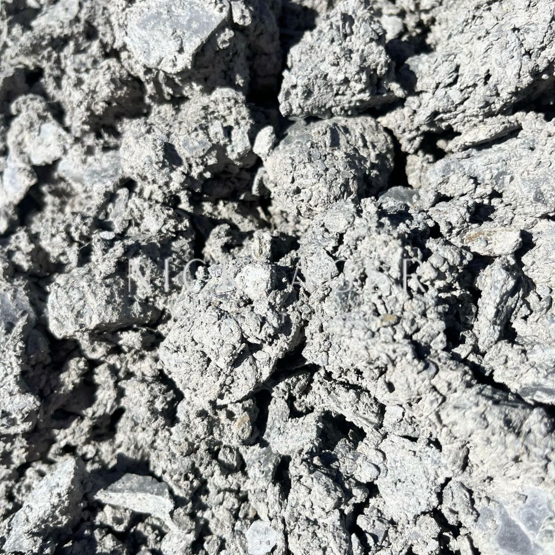 A close-up view of a grey cement mix with a rough, uneven texture, showcasing small lumps and particles.