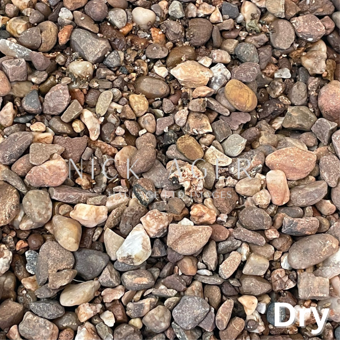 A close-up view of various pebbles in shades of brown, grey, and cream on a dry surface, showcasing their natural textures and shapes.