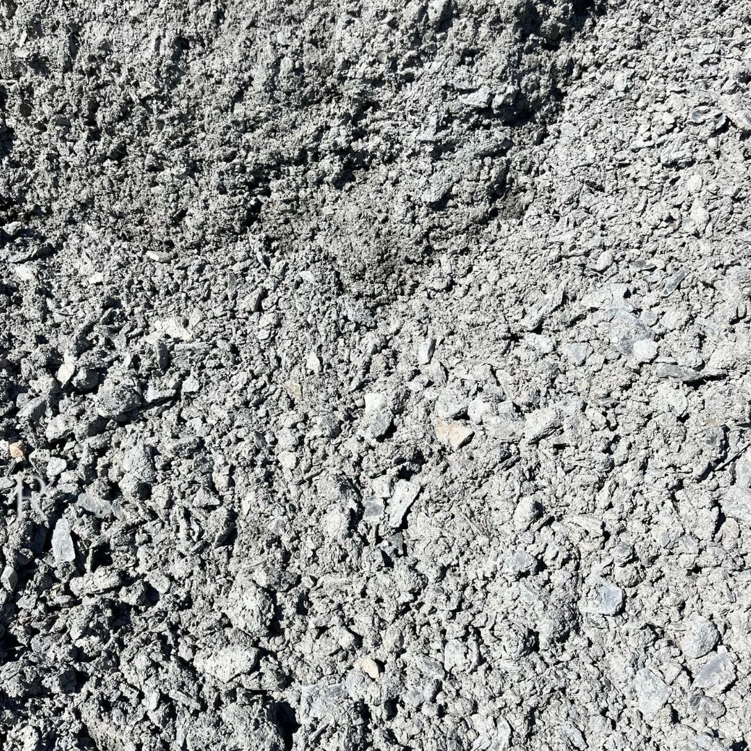 A close-up image showing a rough, uneven surface of grey gravel with varying particle sizes.