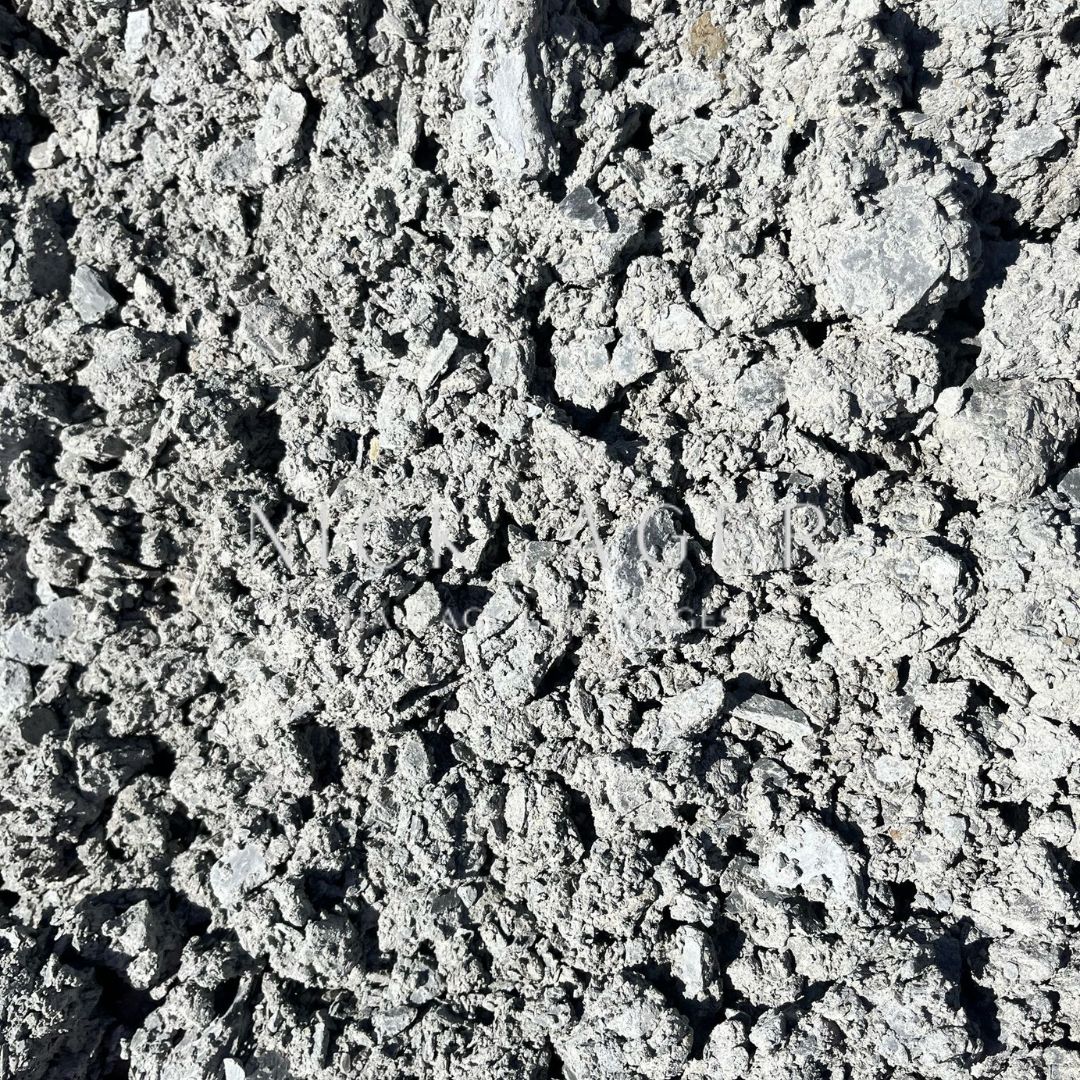 Close-up view of loose, granular grey soil with a rough texture