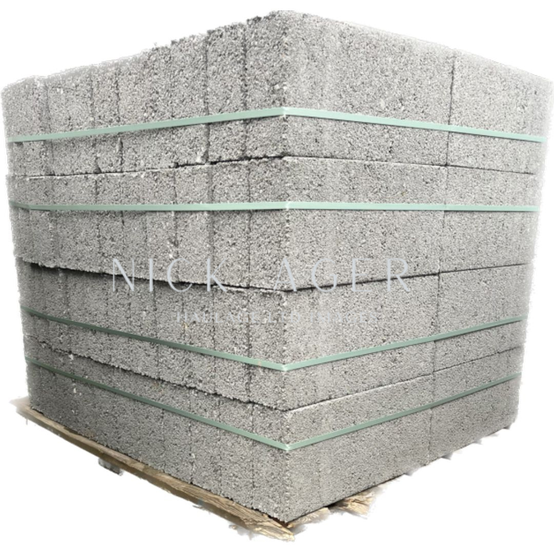 A large stack of grey foam blocks, secured with green straps, resting on a wooden pallet.