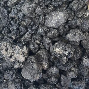 A close-up view of rough black coal clumps scattered on a surface.