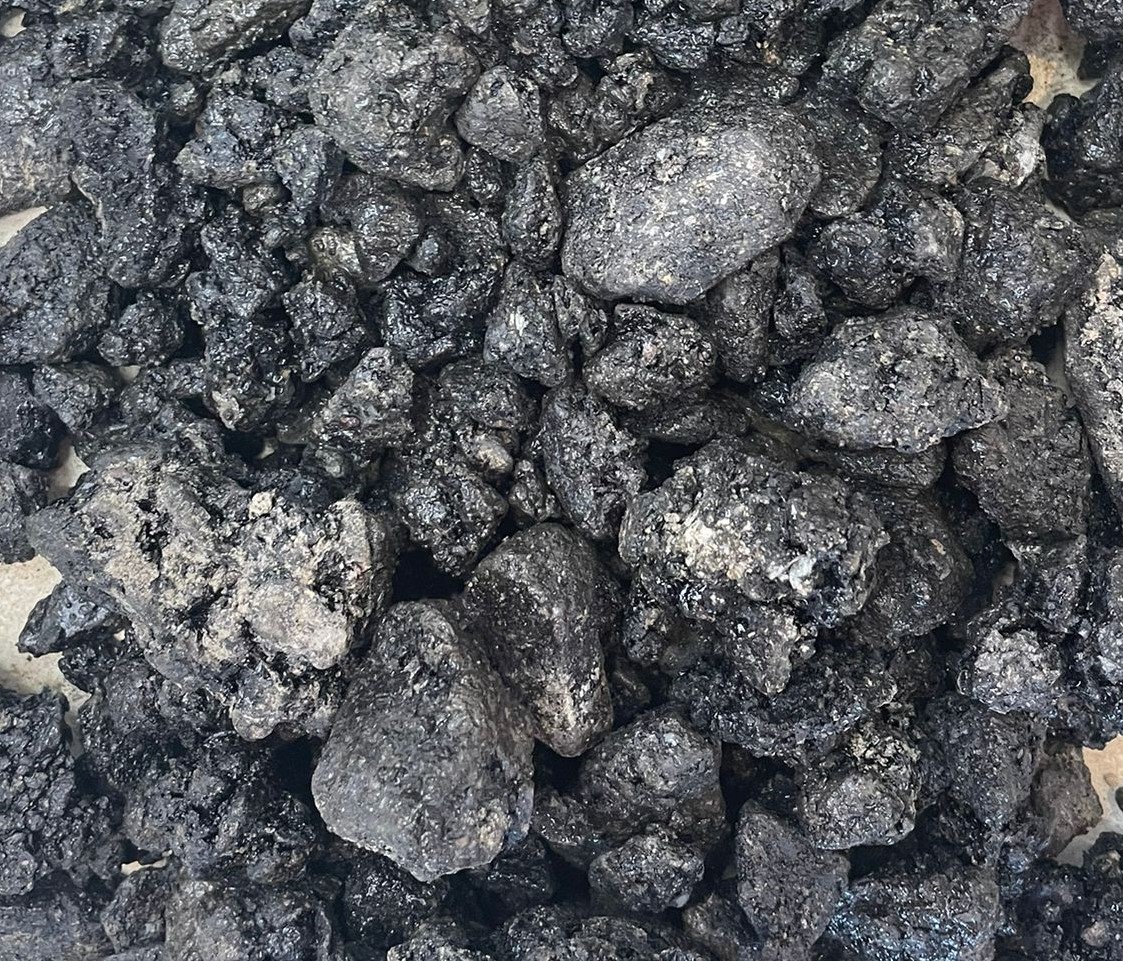 A close-up view of rough black coal clumps scattered on a surface.