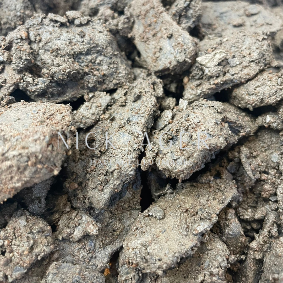 A close-up view of grey crushed earth or soil with a rough texture, featuring irregularly shaped fragments