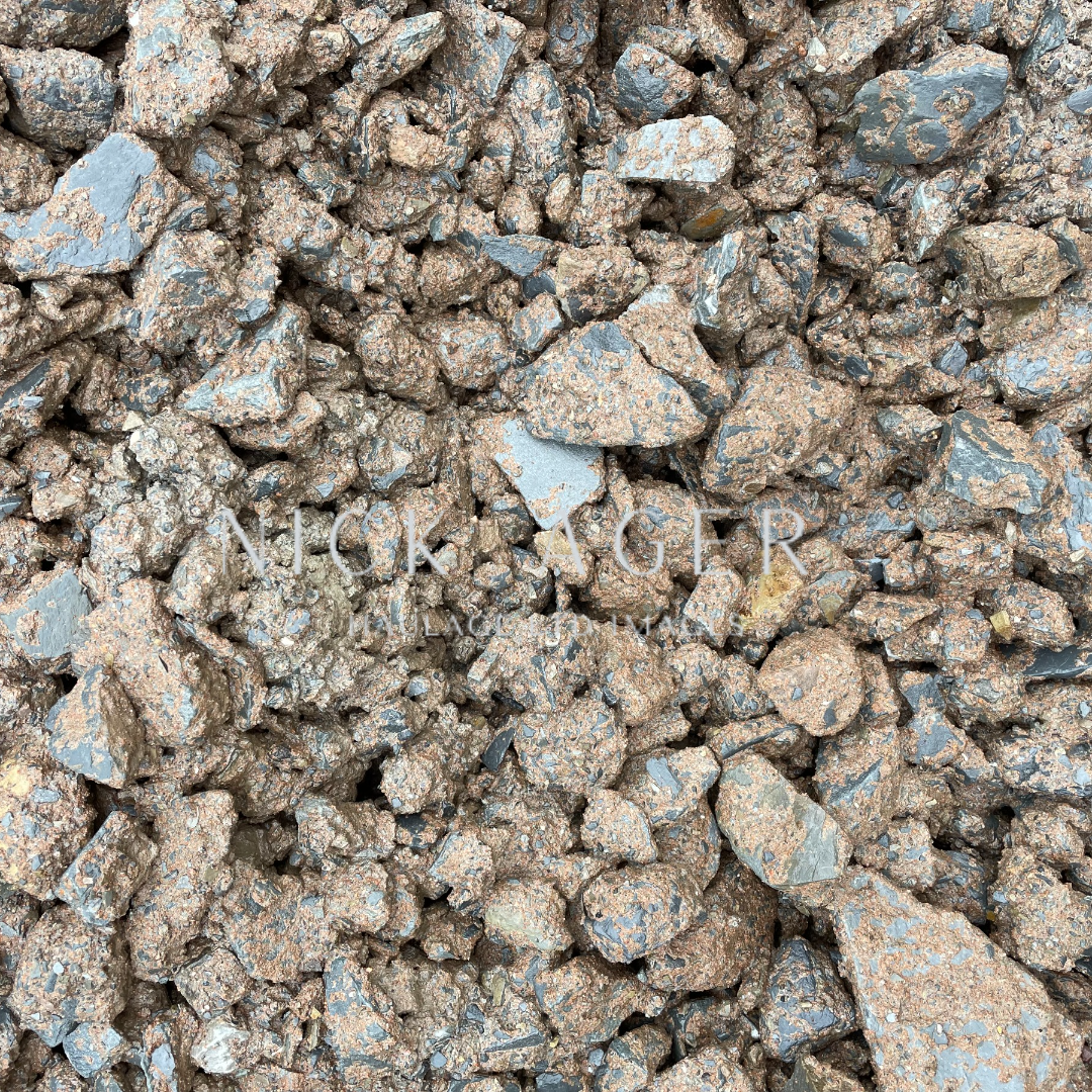 A detailed view of a pile of rocky mineral fragments, showcasing various sizes and textures with a mix of brown and grey tones.