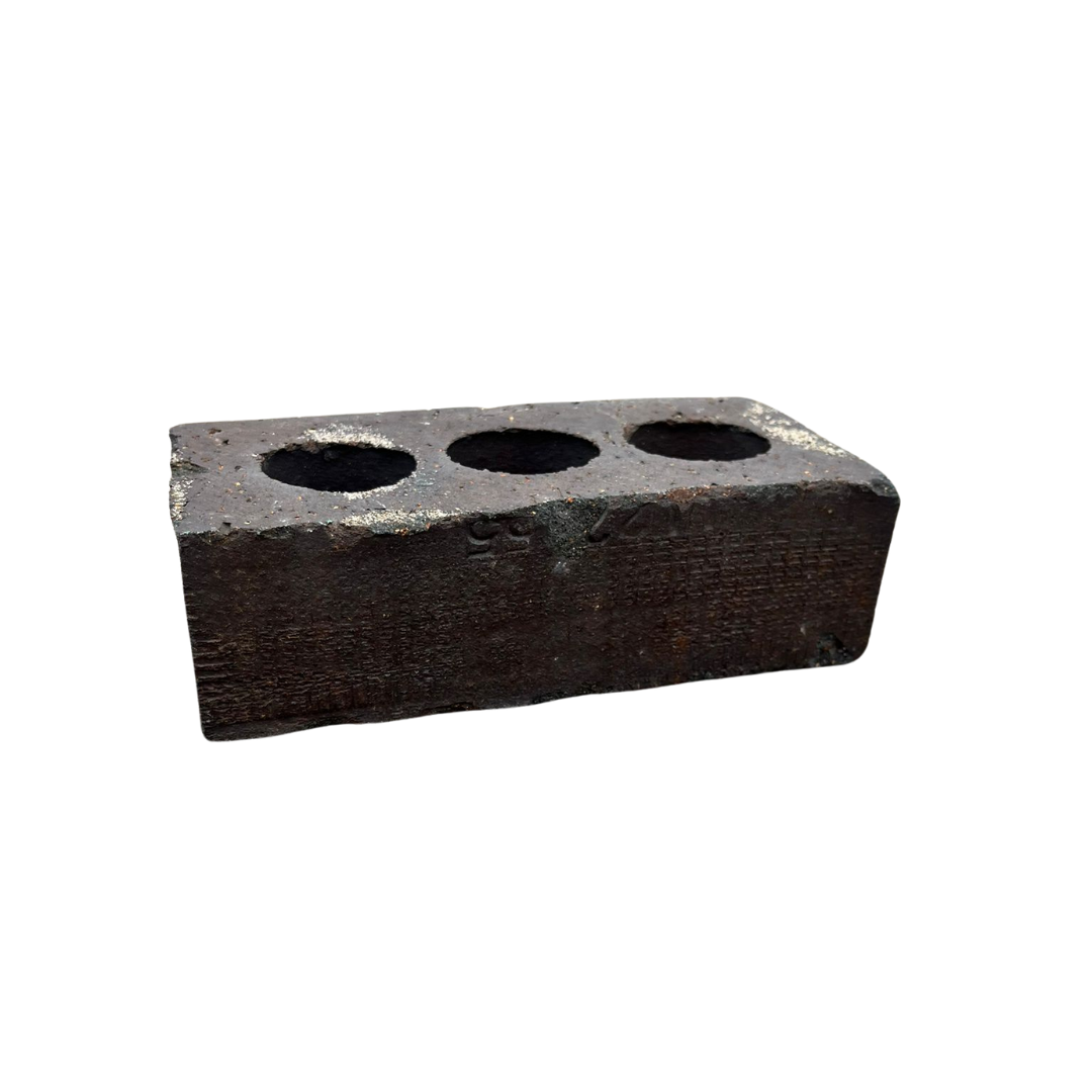 Close-up of a vintage iron block featuring three circular holes, showing signs of wear and rust
