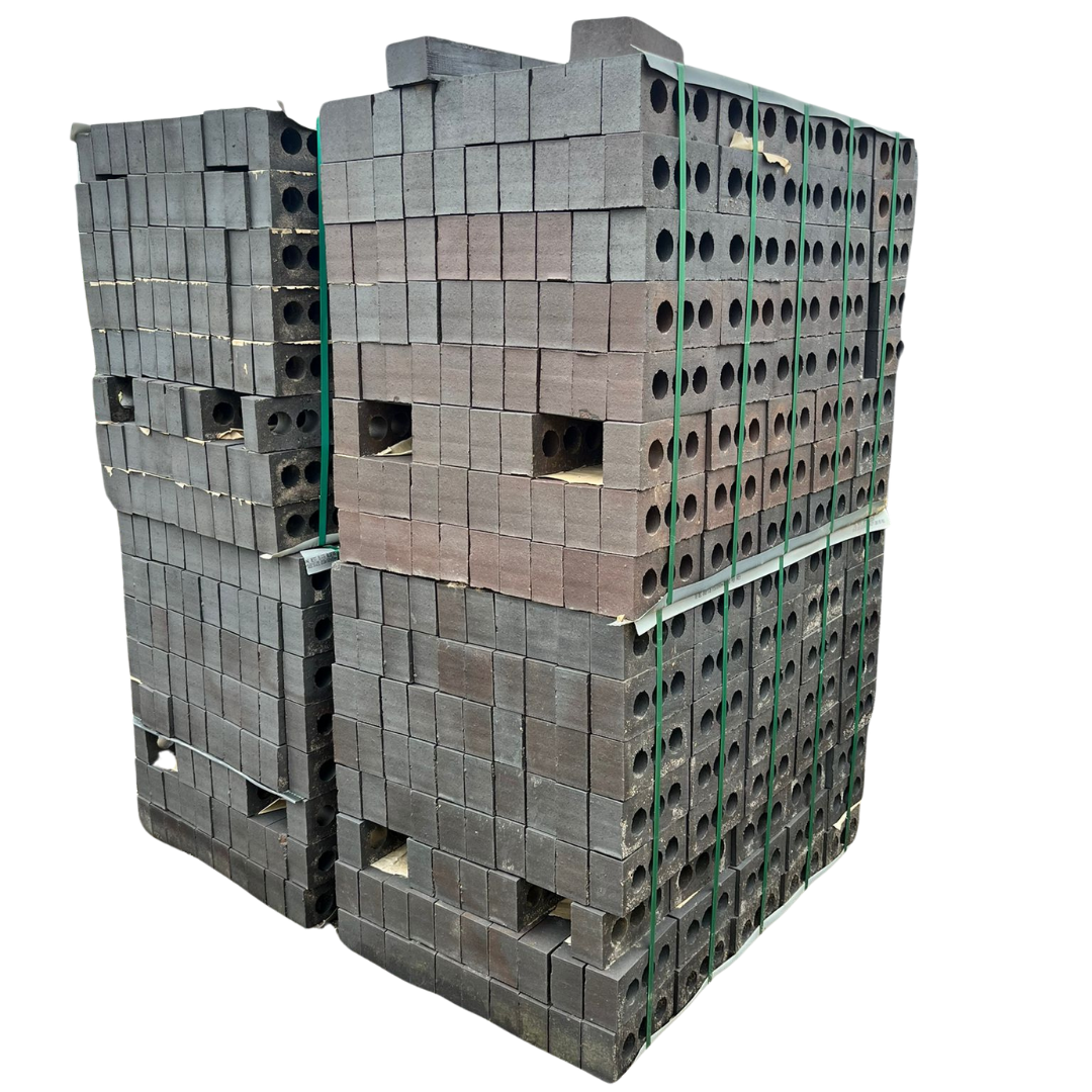 A large stack of rectangular bricks arranged in a neat pile, with multiple holes in some bricks, showcasing different colour variations.