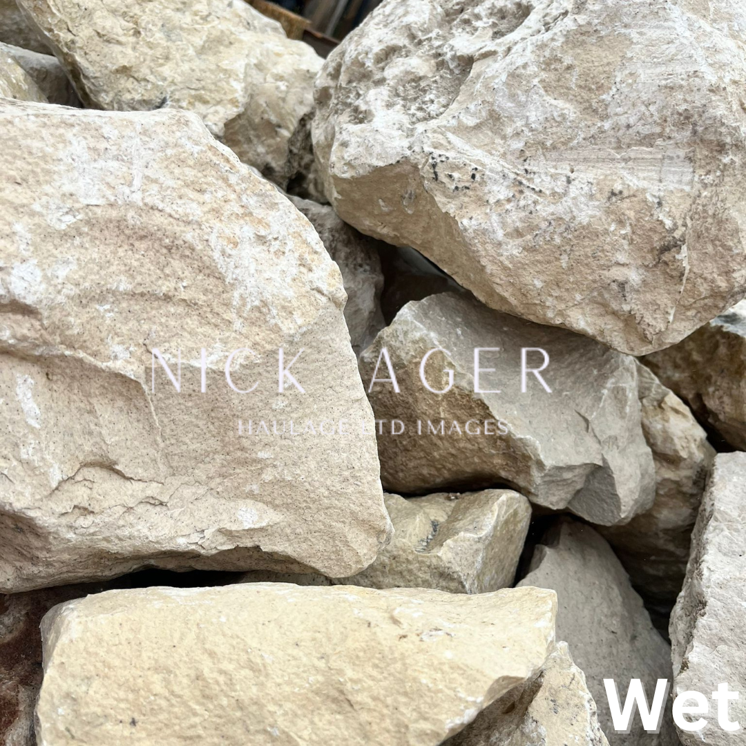 Close-up view of wet natural stone rocks in various shades of grey and beige, showcasing their textured surfaces.