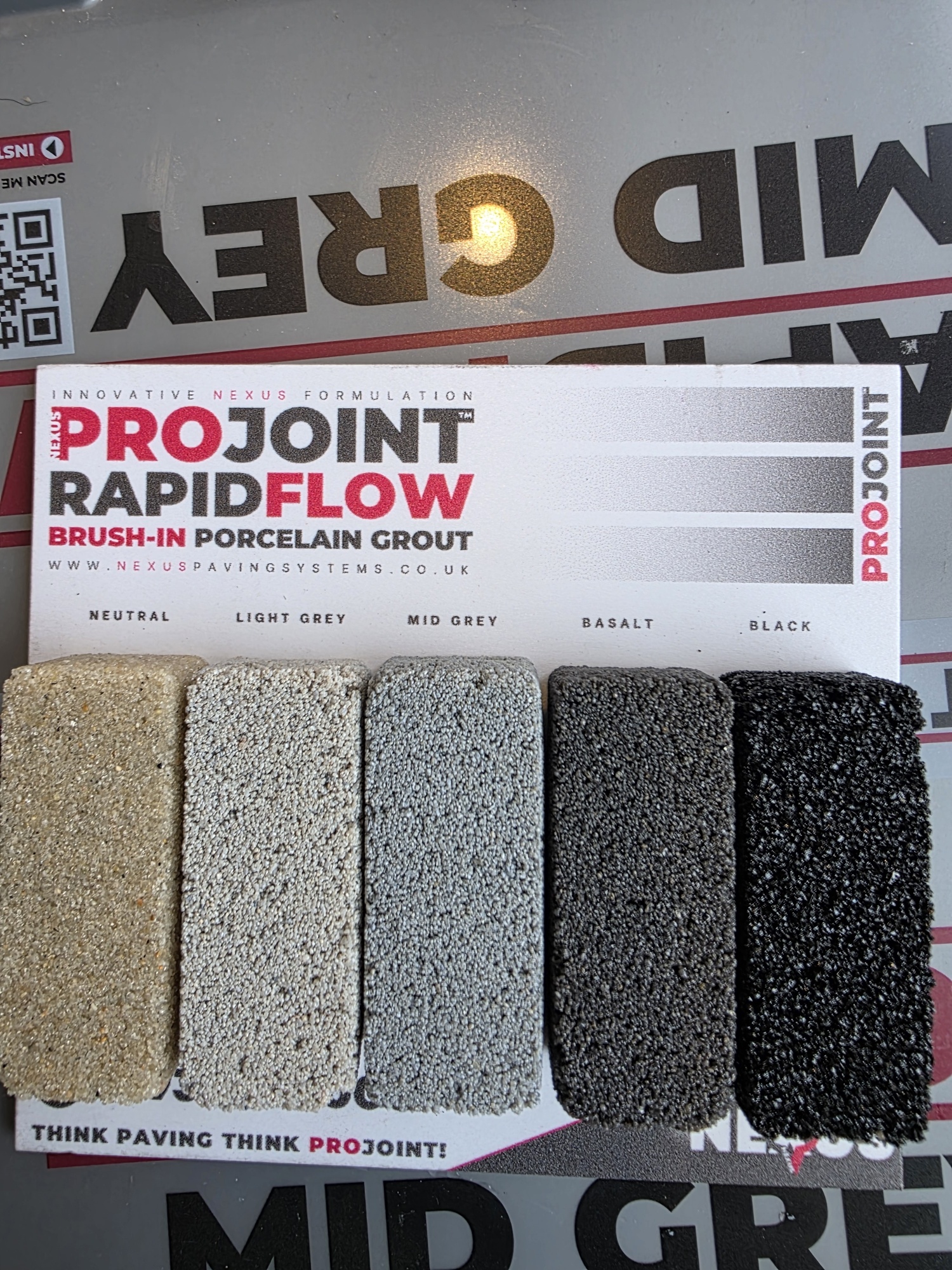 Five sample tiles of ProJoint RapidFlow porcelain grout in neutral, light grey, mid grey, basalt, and black colours displayed on a surface with a grey background.