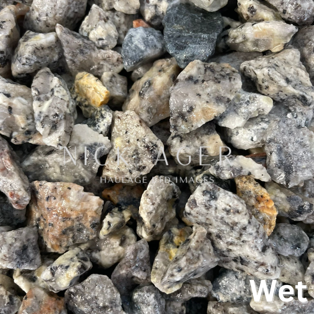 A close-up view of various wet mineral rocks, showcasing a mix of grey, white, and yellowish stones with rough surfaces.