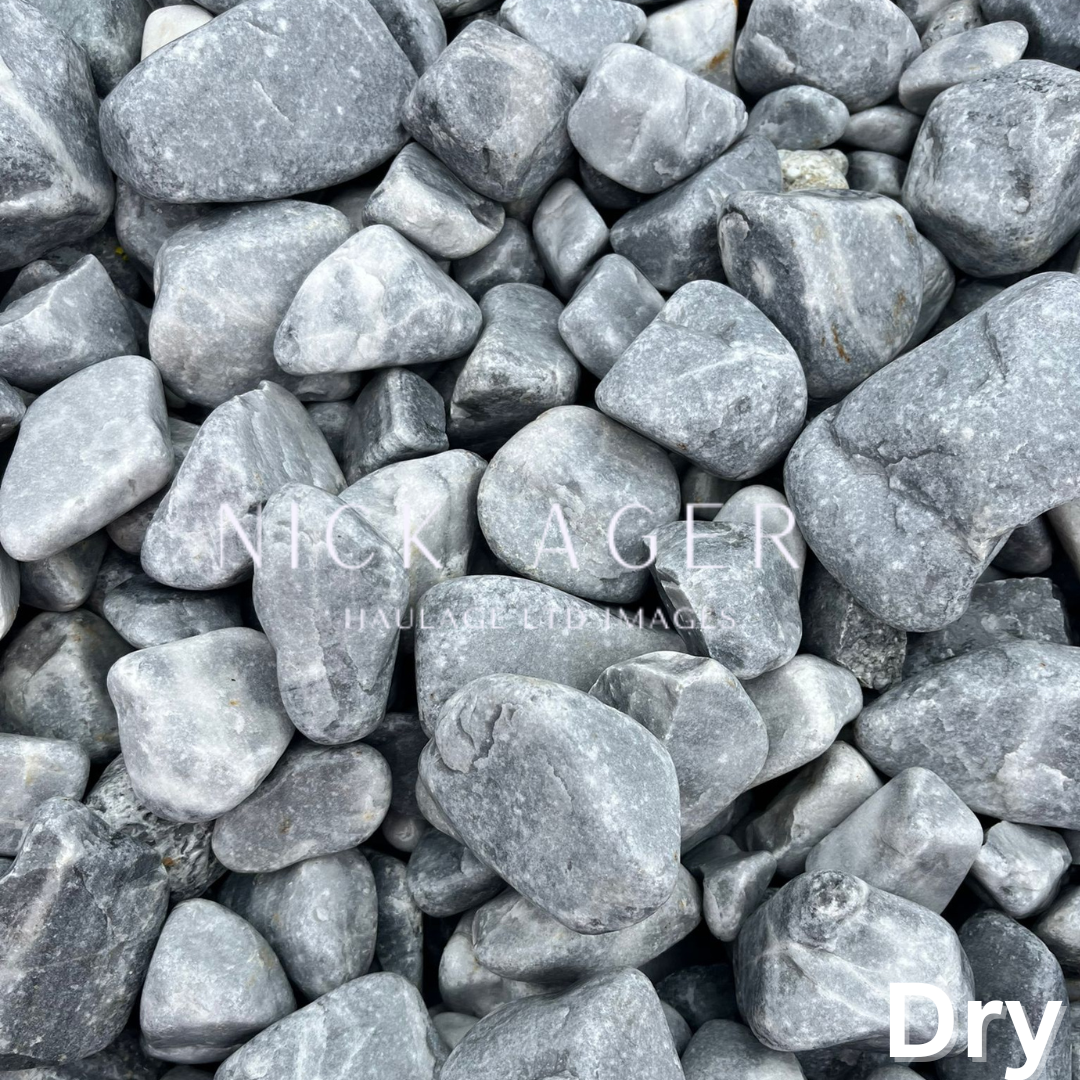 Close-up view of a mixture of grey stones and pebbles with various shapes and sizes, arranged closely together.