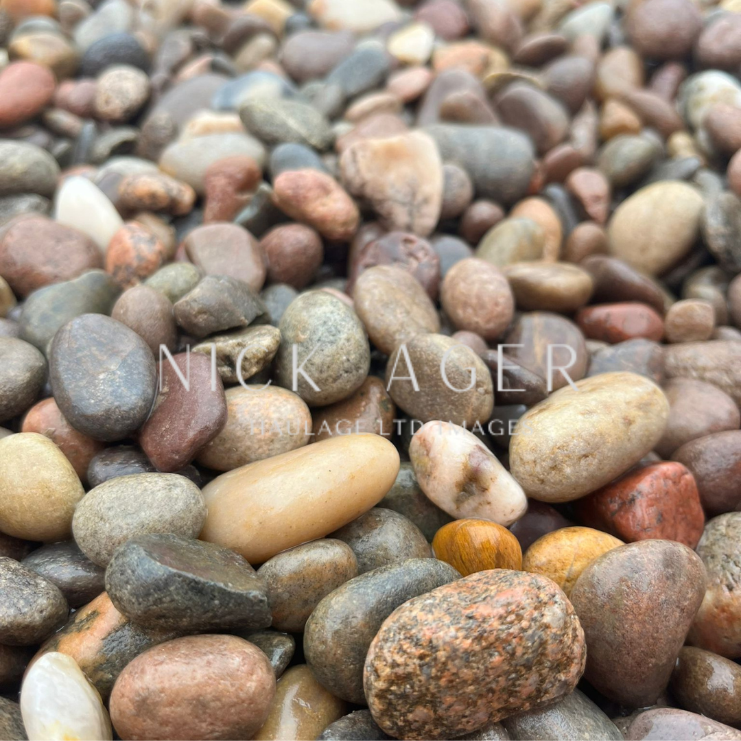 Close-up image of a variety of smooth pebbles in different shapes and colours, including brown, grey, white, and orange.
