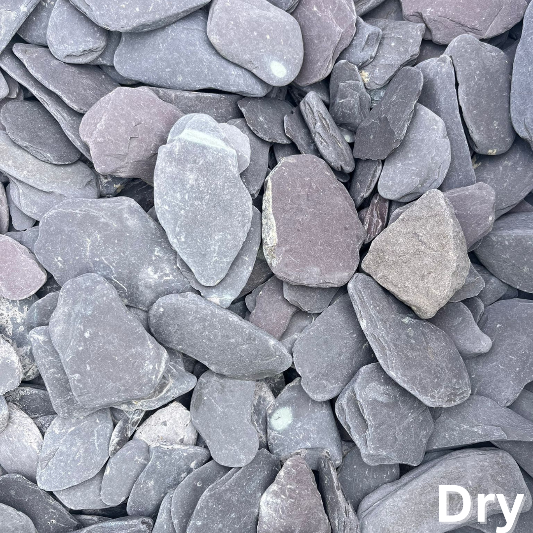 A close-up view of various dry stone pebbles featuring shades of grey and purple, with differing shapes and sizes strewn together.