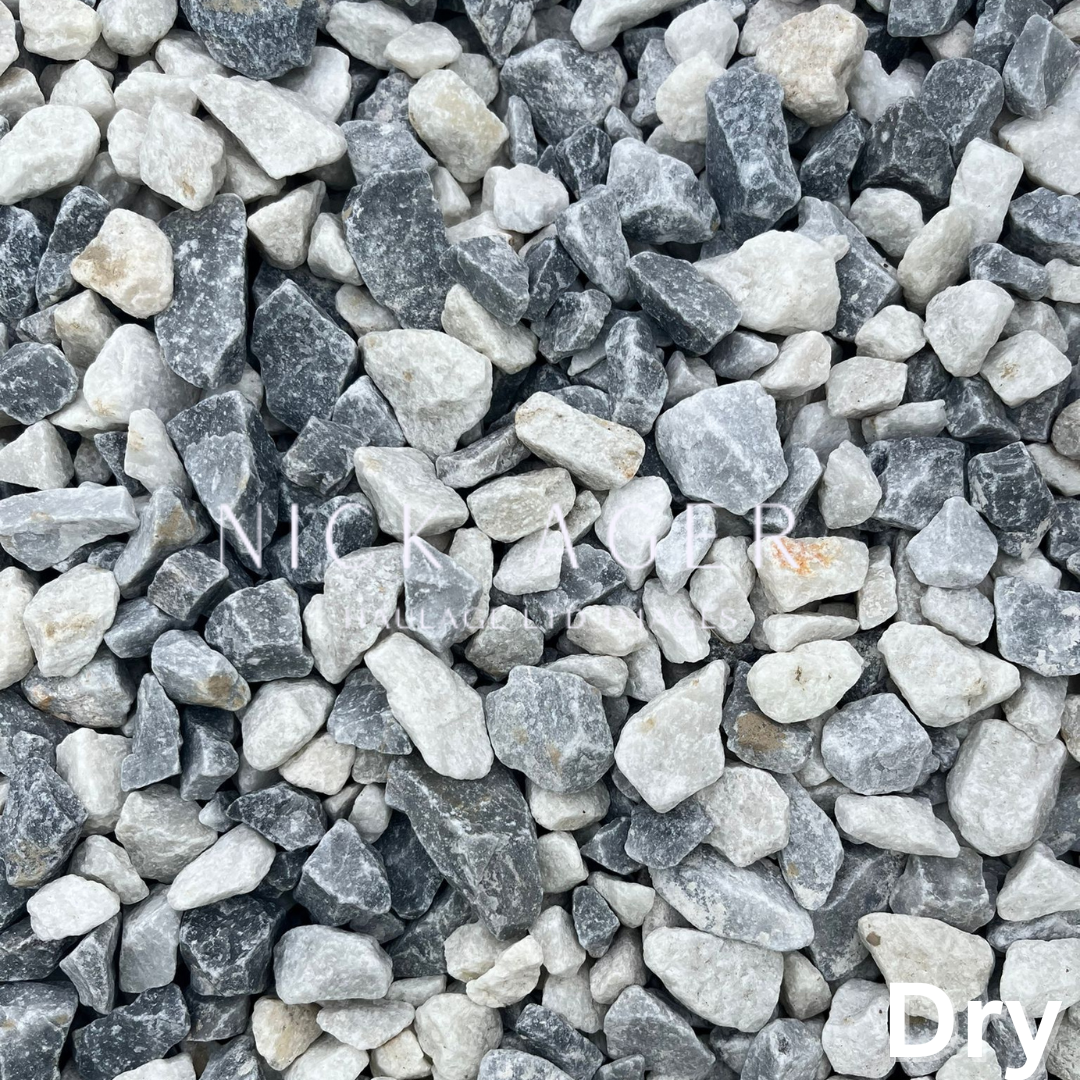 A close-up view of grey and white decorative gravel stones of various sizes and shapes, showing a mixture of dark grey, light grey, and white hues.