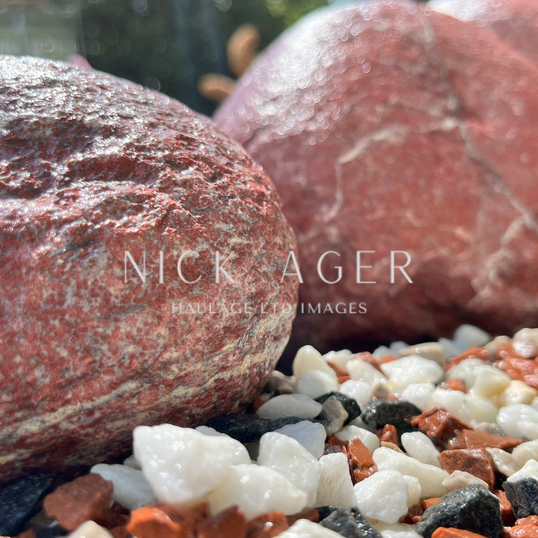 Close-up of textured, reddish stones and small white and brown gravel on a surface, with a blurred background.