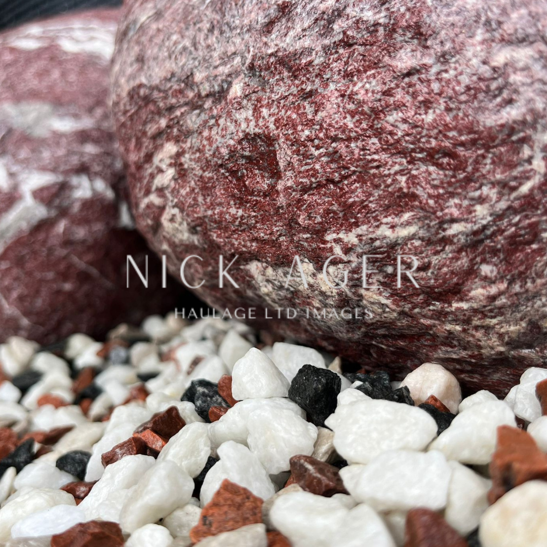 Close-up image showcasing multicoloured decorative gravel with white, black, and reddish stones alongside larger textured rocks.