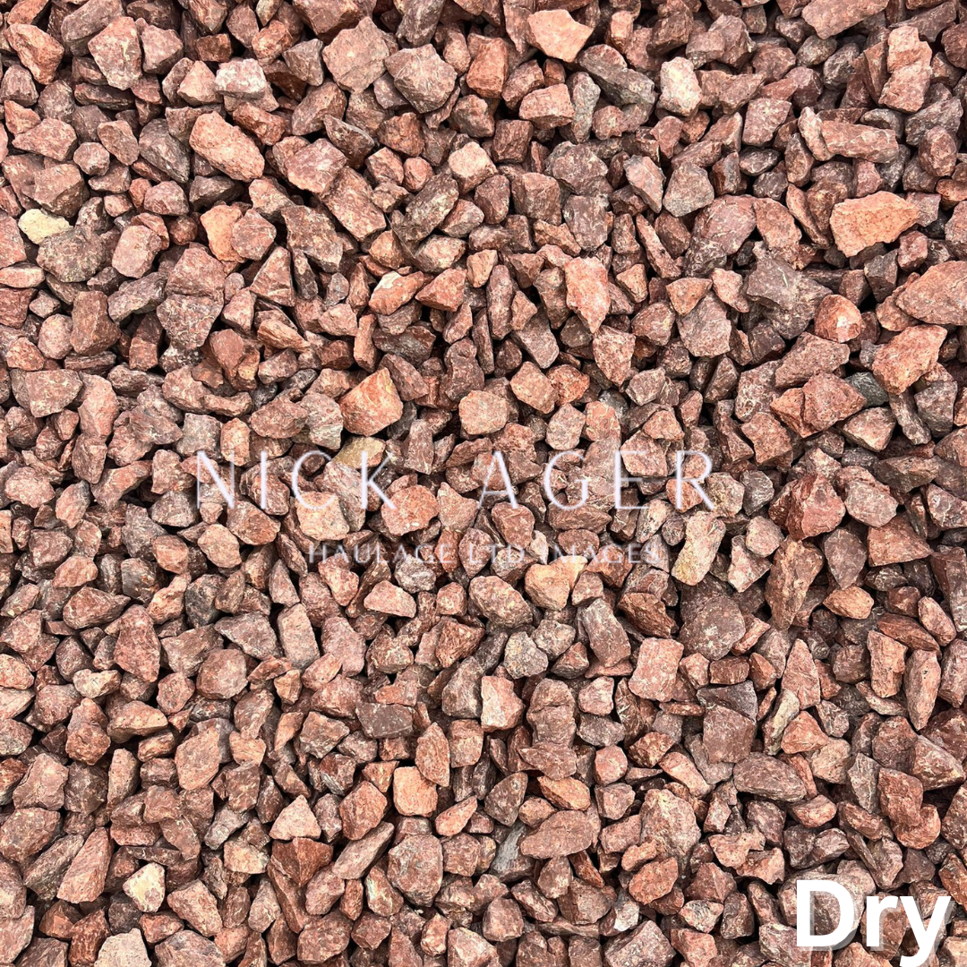 A close-up view of coarse red decorative gravel, featuring small angular stones with various shades of red and brown, dry and suitable for landscaping.