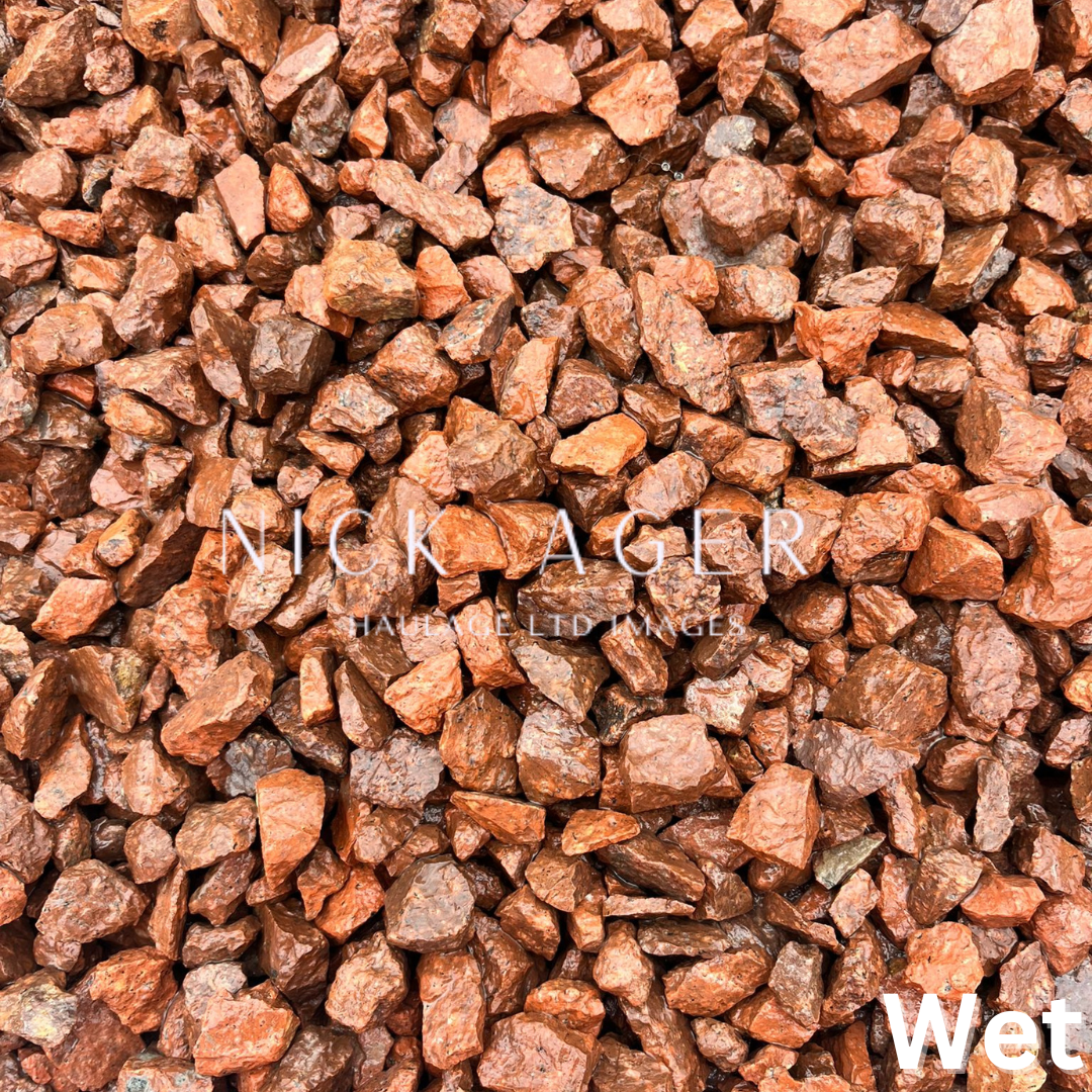Close-up of wet orange-brown decorative gravel stones, showcasing their varied shapes and textures.