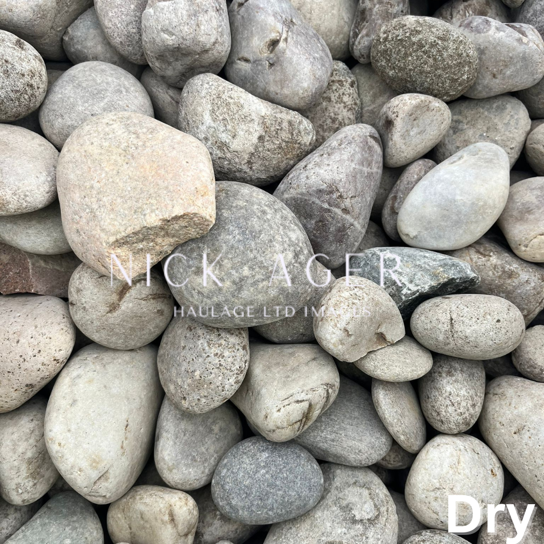 A close-up view of various grey and beige dry stones of different shapes and sizes, piled together.