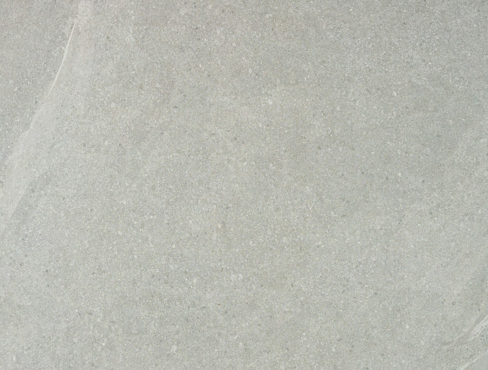 A smooth grey stone surface with subtle variations in texture and colour, featuring a light streak.