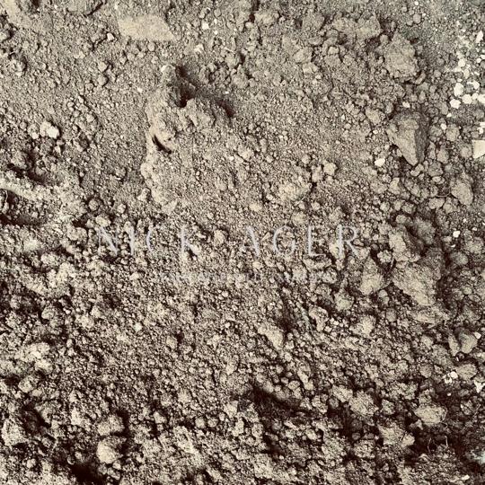 A close-up view of soil showing a mix of fine dirt and small pebbles, with a textured surface and various shades of brown.
