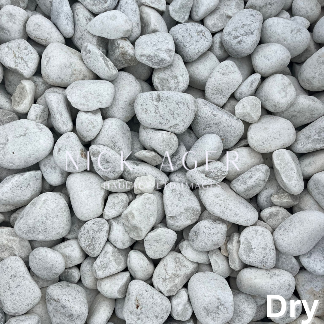 A collection of white cobblestones arranged on a dry surface, suitable for garden pathways or landscaping.
