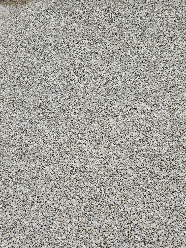 A close-up view of a layer of small, light-coloured gravel stones spread across a surface.
